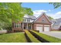 Beautiful brick home featuring an attached garage, manicured shrubs, and green lawn at 121 Cobblepoint Way, Holly Springs, NC 27540