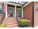 Inviting front porch with brick steps and detailed columns, creating a warm entry at 121 Cobblepoint Way, Holly Springs, NC 27540