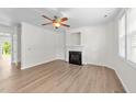 Bright living room featuring a fireplace, ceiling fan, and attractive wood flooring at 125 Occidental Dr, Holly Springs, NC 27540