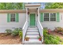 Charming home featuring a bright green front door, complemented by matching shutters and lovely landscaping at 1703 Cranston Road Rd, Garner, NC 27529