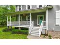 Inviting front porch featuring a teal door, white railings, and decorative hanging plants at 179 Carrie Dr, Archer Lodge, NC 27527