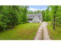 Spacious front yard showcasing a well-maintained lawn, mature trees, and long gravel driveway at 179 Carrie Dr, Archer Lodge, NC 27527