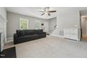 Spacious living room features carpeted floors, ceiling fan, staircase, and a large grey sofa at 2028 Ruddy Rd, Raleigh, NC 27616