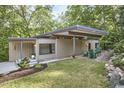 Contemporary home with a flat roof, green lawn, natural landscaping, and outdoor seating area at 220 Glenhill Ln, Chapel Hill, NC 27514
