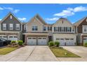 Street view of townhomes featuring two-car garages and well-maintained landscaping under a clear, sunny sky at 4137 Lofty Ridge Pl, Morrisville, NC 27560