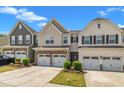 Street view of townhomes featuring two-car garages and well-maintained landscaping under a vibrant blue sky at 4137 Lofty Ridge Pl, Morrisville, NC 27560