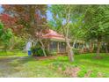 Inviting two-story home with a metal roof, front porch, and mature trees in a lush green yard at 429 N Asheboro St, Liberty, NC 27298