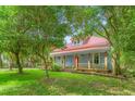 Charming two-story home with a red metal roof, a inviting front porch, and mature trees in a lush green yard at 429 N Asheboro St, Liberty, NC 27298