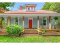 Inviting front porch with wood columns, railings, hanging plants, and a bright red door adds a touch of character at 429 N Asheboro St, Liberty, NC 27298