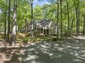 A picturesque view of a two-story home surrounded by lush trees and a spacious gravel driveway at 6000 Canadero Dr, Raleigh, NC 27612