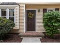 Close-up of front door featuring a colorful wreath and neat landscaping at 7015 Staghorn Ln, Raleigh, NC 27615