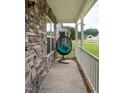 Cozy covered porch featuring stone accents, white railings, and a comfortable hanging chair at 71 Hunters Way, Angier, NC 27501