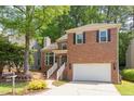 Two-story brick home with black shutters, an attached garage, and mature trees at 8124 Greywinds Dr, Raleigh, NC 27615