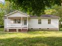 Quaint one-story home with white siding, front porch, and mature trees at 84 Honeysuckle Dr, Pittsboro, NC 27312