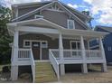 The front of this home features a welcoming covered porch, complemented by gray siding and a gabled roofline at 1005 Forrestal Pl, Durham, NC 27707