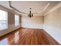Formal dining room with hardwood floors, chandelier, wainscoting, and large windows at 102 Revere Forest Ct, Cary, NC 27519