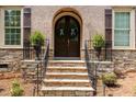 Close-up of the arched brick entryway with a stone staircase and decorative potted plants at 112 Aspenridge Dr, Holly Springs, NC 27540