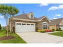 Single-story home featuring stone details, a two-car garage, and nicely kept landscaping at 122 Tall Timber Dr, Gibsonville, NC 27249