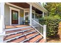 Inviting covered front porch with wooden flooring, classic columns, and a cozy seating area at 1241 Dalgarven Dr, Apex, NC 27502