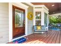 Close-up of front door entrance to front porch with seating, floral mat, and wreath at 1241 Dalgarven Dr, Apex, NC 27502