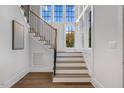 Staircase with hardwood steps and floors, metal handrail, and large windows to bring in natural light at 1400 Hedgelawn, Raleigh, NC 27615