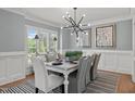 Elegant dining room features modern chandelier, wainscoting, a striped rug and windows with plantation shutters at 14013 Wallberman Dr, Wake Forest, NC 27587