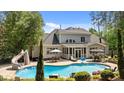Backyard with a large, sparkling pool, a waterslide, patio seating, and mature landscaping at 14013 Wallberman Dr, Wake Forest, NC 27587