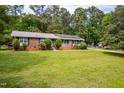 Ranch style home with brick facade, solar panels, manicured bushes, and a green lawn at 149 Baldwin Dr, Durham, NC 27712