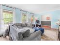 Inviting living room with a comfortable gray sectional, large windows, and a stylish blue ottoman at 149 Baldwin Dr, Durham, NC 27712