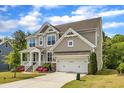 Attractive two-story home featuring a lush green lawn, colorful flower beds, and an attached two-car garage at 1811 Sandoval Dr, Durham, NC 27703