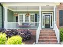 Inviting front porch with white railings, hanging flower baskets, and brick steps at 2633 Penfold Ln, Wake Forest, NC 27587