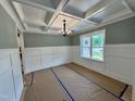 Dining room with coffered ceilings, white wainscoting, and a window providing natural light at 27 Batten Hill Ln, Selma, NC 27576