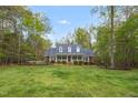 Traditional home with a blue roof, brick accents, white porch, and large front yard surrounded by mature trees at 2925 Ericka Dr, Hillsborough, NC 27278