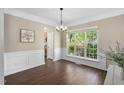 Well-lit dining room features hardwood floors, wainscoting, a modern chandelier, and a large window for ample natural light at 3302 Colorcott St, Raleigh, NC 27614