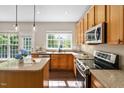 Spacious kitchen with stainless steel appliances, wooden cabinets, granite countertops, and a central island with stylish pendant lighting at 3302 Colorcott St, Raleigh, NC 27614