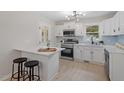 Modern kitchen with white cabinets, stainless steel appliances, a breakfast bar, and sleek light fixtures at 3408 Brentwood Rd, Raleigh, NC 27604