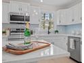 Modern kitchen with stainless steel appliances, a marble island, and bright white cabinets with contemporary lighting at 3408 Brentwood Rd, Raleigh, NC 27604