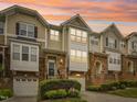 Beautiful multi-level townhouse showcasing stone accents, a garage, and well-maintained landscaping under a vibrant sunset at 5026 Celtic Ct, Raleigh, NC 27612