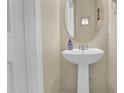 Cozy powder room featuring a pedestal sink, oval mirror, and fresh design, located on the main floor at 503 Bellefont Ct, Knightdale, NC 27545
