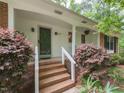 Close-up of the front porch with wooden stairs, decorative bushes and a glimpse of the front door at 508 Colony Woods Dr, Chapel Hill, NC 27517