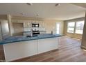 A well-lit kitchen with hardwood flooring, island, and modern stainless steel appliances at 56 Ruskin Dr, Smithfield, NC 27577