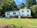 Charming white two-story home with a teal front door, mature landscaping, and a well-maintained lawn at 5817 Wintergreen Dr, Raleigh, NC 27609