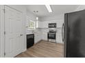 Kitchen with white cabinets, black appliances, stainless steel oven, and hardwood floors at 620 Hanska Way, Raleigh, NC 27610