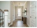 Bright entryway featuring hardwood floors, a decorative light fixture, and a staircase at 737 W Holly Springs Rd, Holly Springs, NC 27540