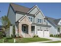 Charming home featuring stonework, a two-car garage, and manicured lawn under clear blue skies at 737 W Holly Springs Rd, Holly Springs, NC 27540