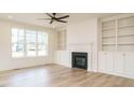 Bright living room with modern ceiling fan, fireplace, built-in shelving and large window at 749 W Holly Springs Rd, Holly Springs, NC 27540