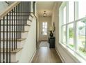 Elegant hallway with hardwood floors, stairs, a modern light fixture and an abundance of natural light at 755 W Holly Springs Rd, Holly Springs, NC 27540