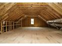 Unfinished attic space with exposed wood beams, a small window, and ample room for storage or conversion at 761 W Holly Springs Rd, Holly Springs, NC 27540