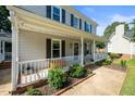 Inviting front porch with white railing, black shutters, and colorful landscaping around the front yard at 8009 Tobin Pl, Raleigh, NC 27612