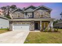 Charming two-story home with stone accents, a paved driveway, and a two-car garage at sunset at 8013 Toddwick Ct, Raleigh, NC 27616